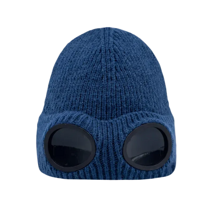 A blue ribbed knit beanie hat with two large black oval visor-like cutouts on the front, shown against a plain white background.