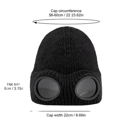 Black knit ski cap with integrated goggles, shown with measurement labels and arrows indicating cap circumference, hat brim, cap depth, and cap width on a white background.